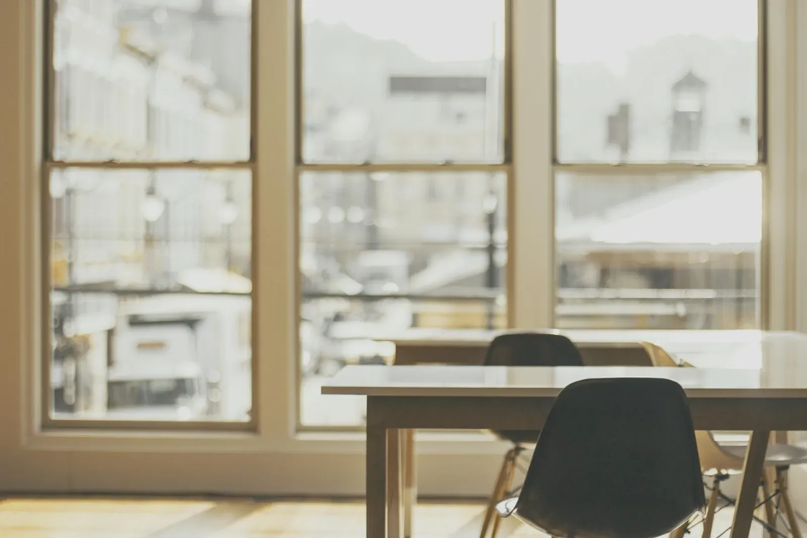 A bright, uncluttered workspace with tall windows and empty desks